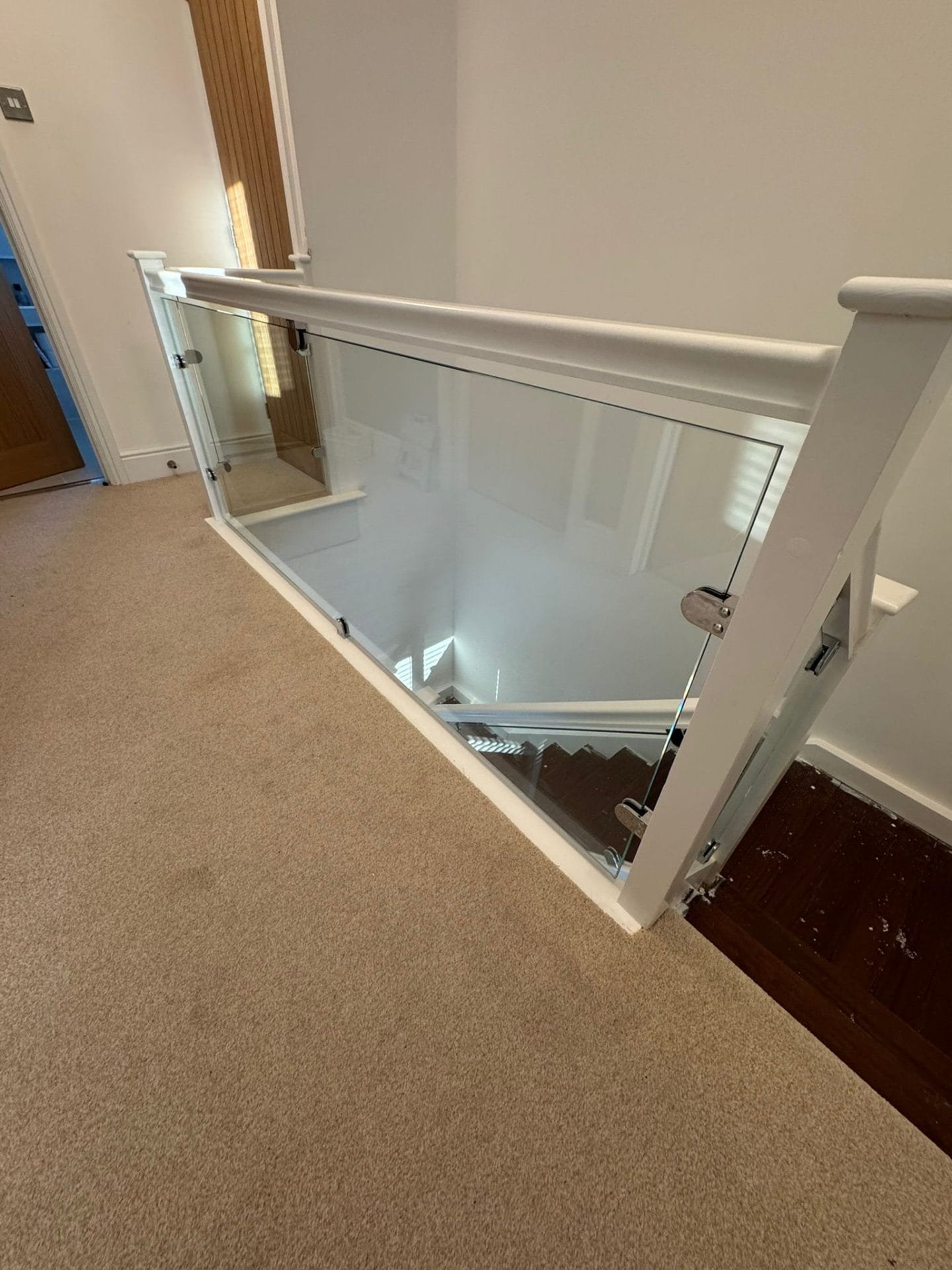 features a modern glass balustrade with a white wooden handrail.